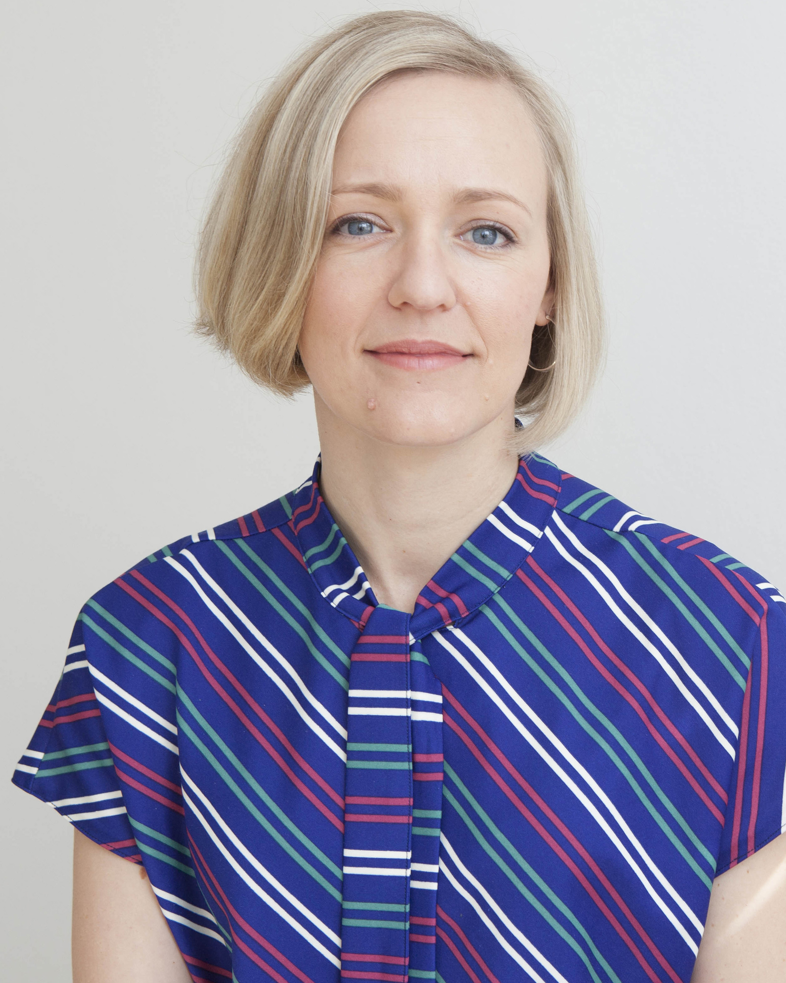 A photo of Rochelle Haley wearing a blue, pink, green, and white striped shirt.