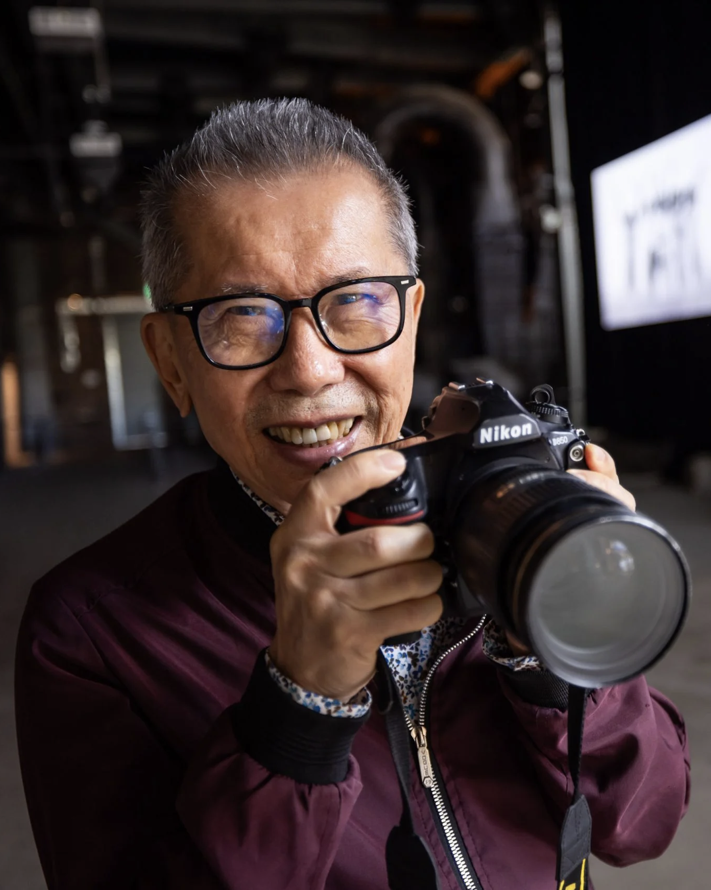 Portrait of artist William Yang holding a camera