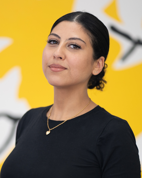 Portrait of artist Leila el Rayes on a yellow background.