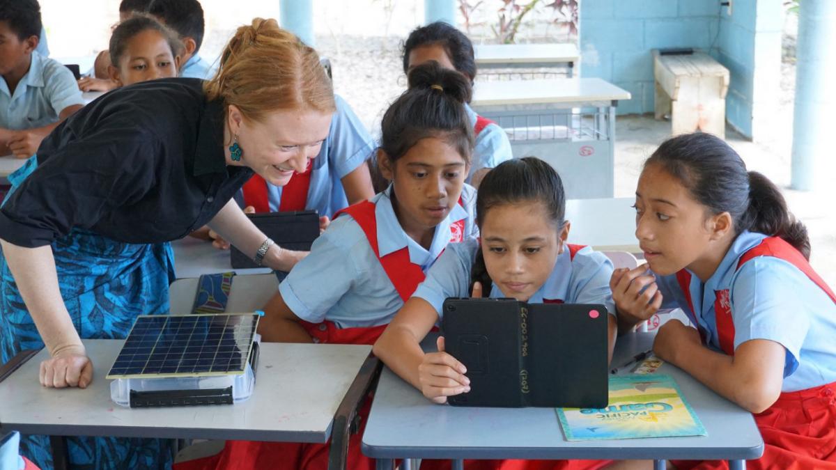 photo of Laura Hosman with school students looking at a tablet computer