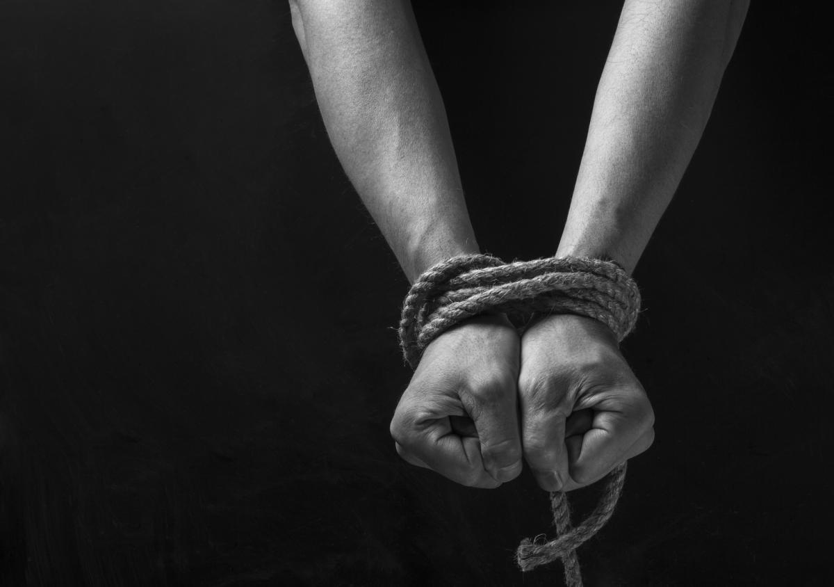photo of hands tied in rope behind a back