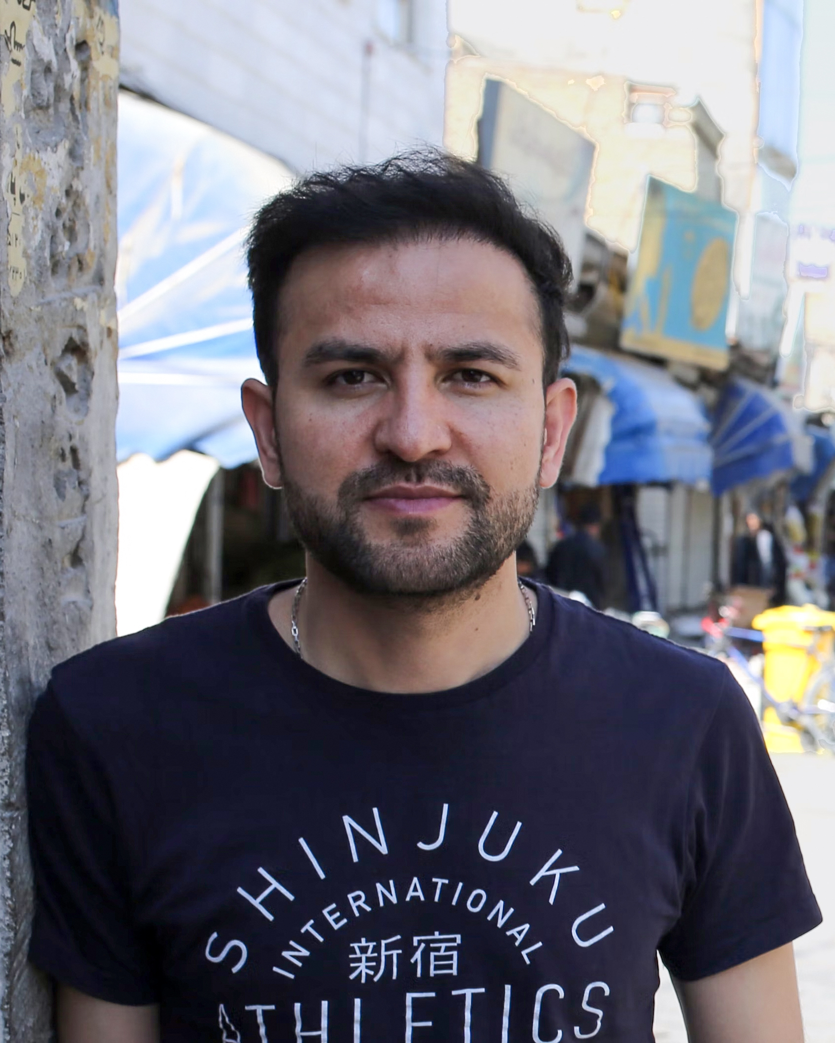 Portrait of artist Elyas Alavi on a busy street.