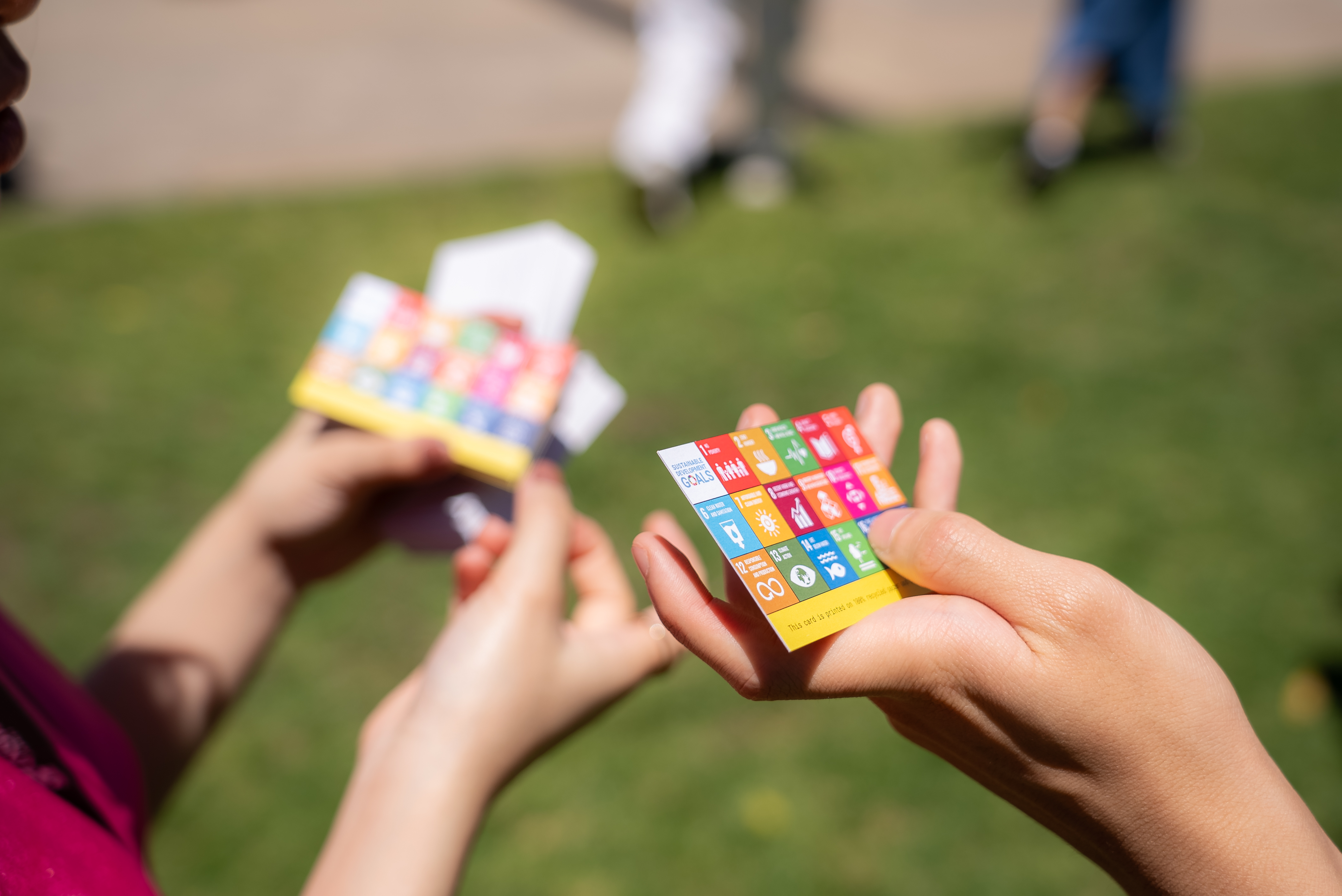 Hands holding paper cards displaying the SDGs