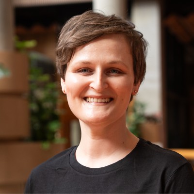 A woman with short hair and a black t-shirt smiles at the camera.