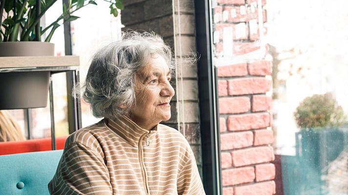 photo of an older women sitting and staritng into the distance