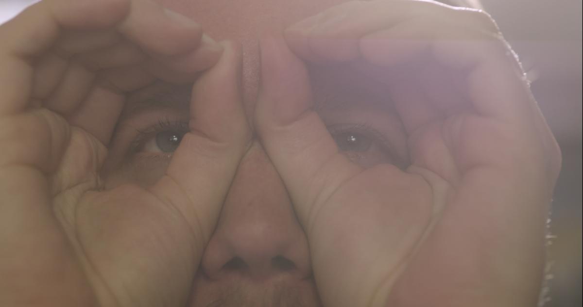 hazy photo of a man's face with hands in front of eyes
