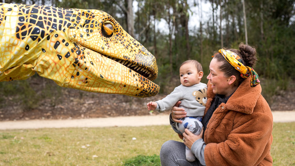 Image of family and baby patting a dinosaur