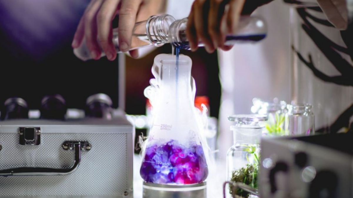 scientist hands mixing cocktail in a beaker