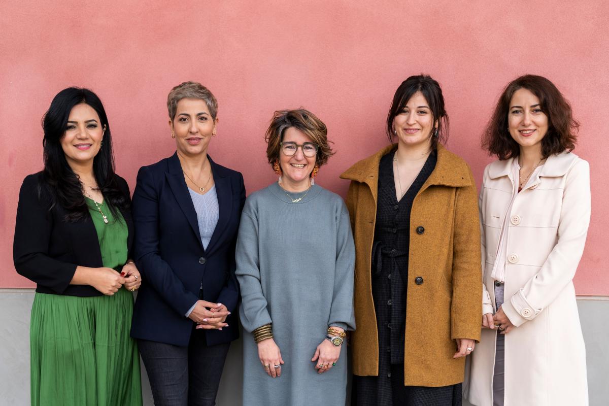 Five women standing in front of a pink wall