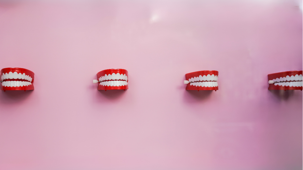 four mechanical teeth mounted on a pink wall
