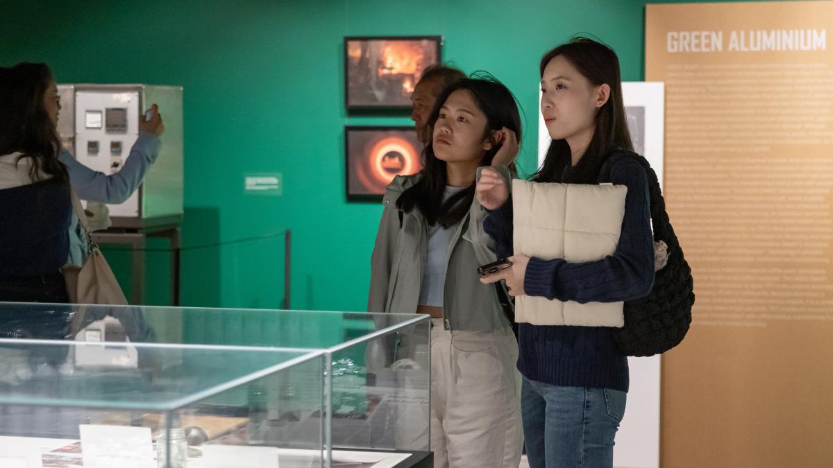 Two woman view a gallery space with green walls