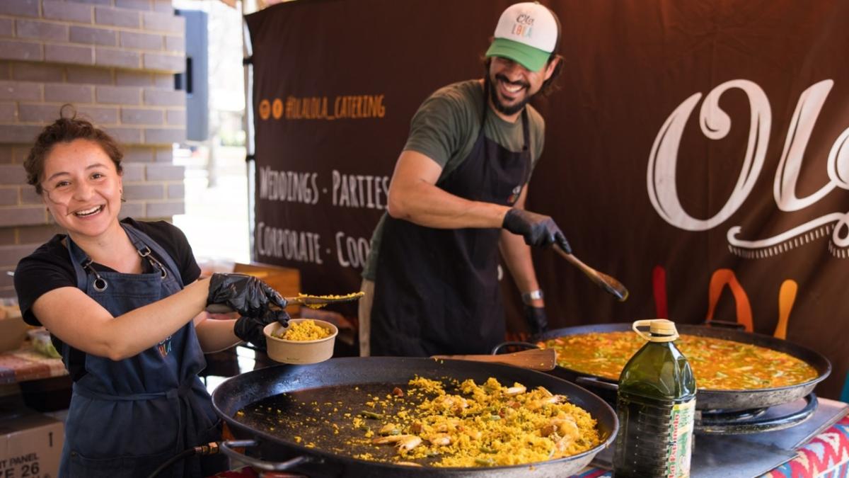 Two people cooking paella