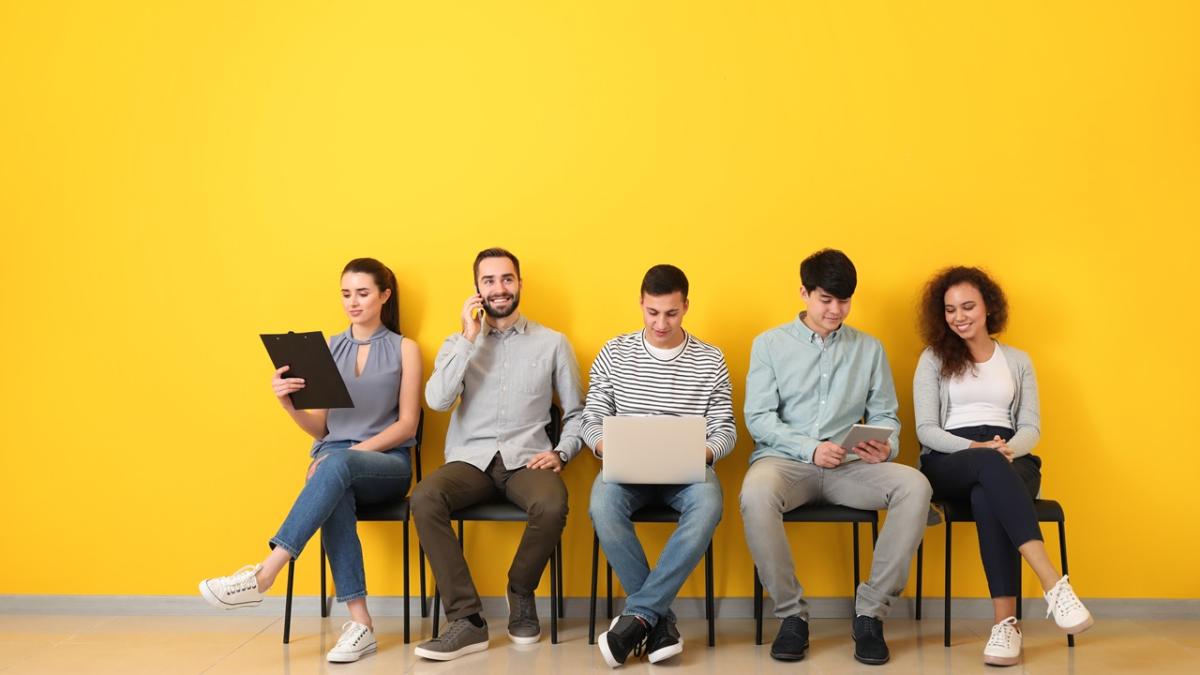A group of people seated against a yellow wall