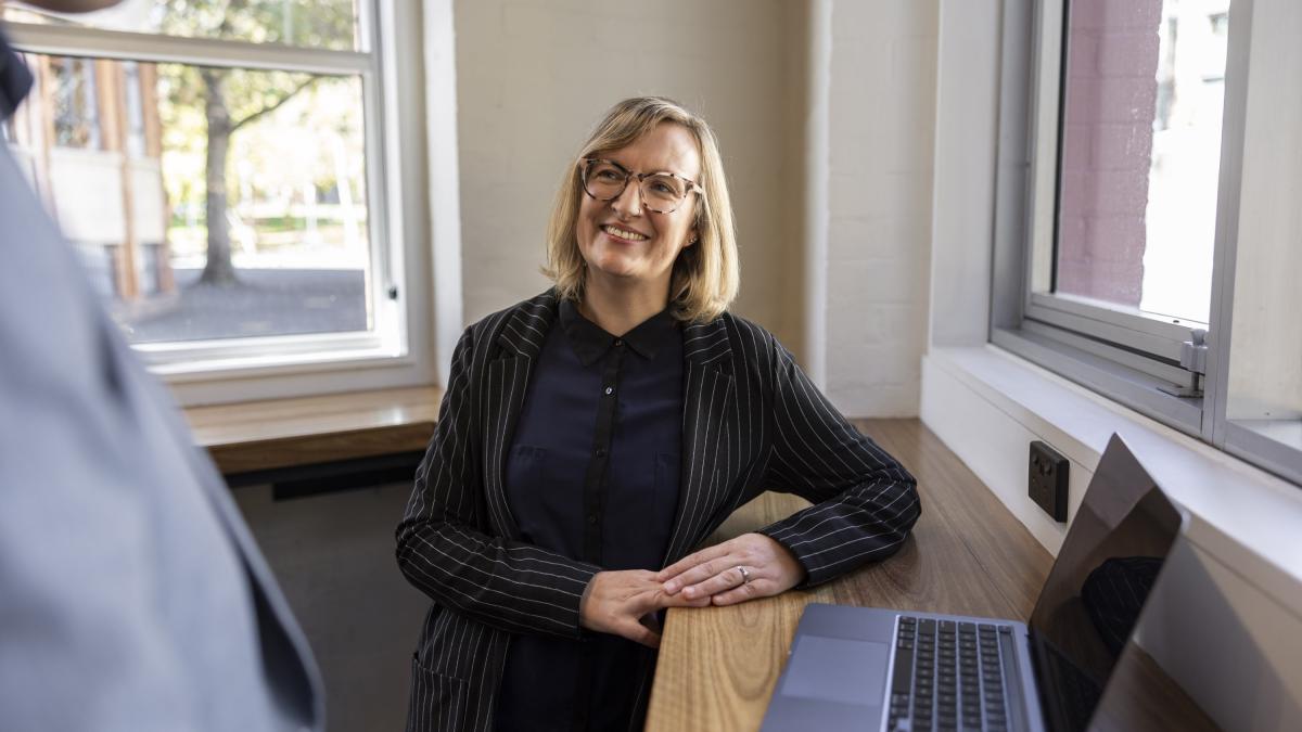 woman leaning on desk with laptop